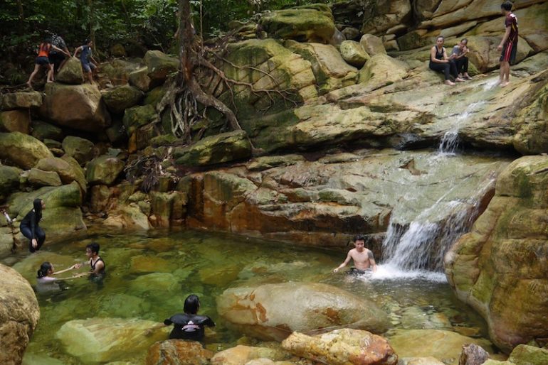 People swimming and soaking at the Satubong Waterfall