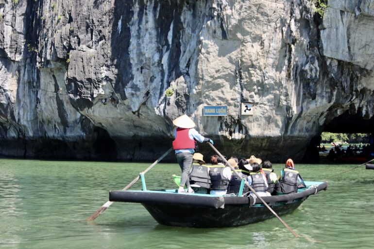 Vietnamese rowing the traditional raft towards Luon Cave lagoon