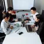 Team working on laptops around a meeting table – 10 CENTS CAPITAL US$20 million for AI and cross-border B2B