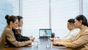 Team on a video call around a conference table – 10 CENTS CAPITAL global multilingual marketing.